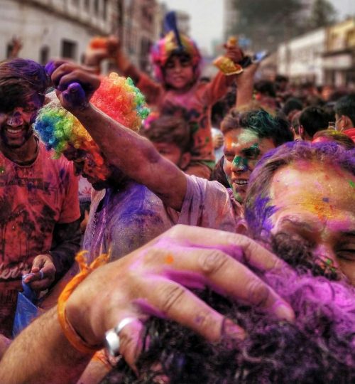Colorful celebration of Holi Festival in Gorakhpur, India with joyful crowd covered in powders.